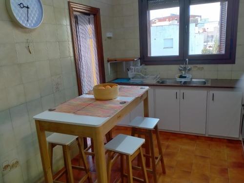 - une cuisine avec une table, des tabourets et un évier dans l'établissement Ca l'Aiguadora, à Sant Mateu