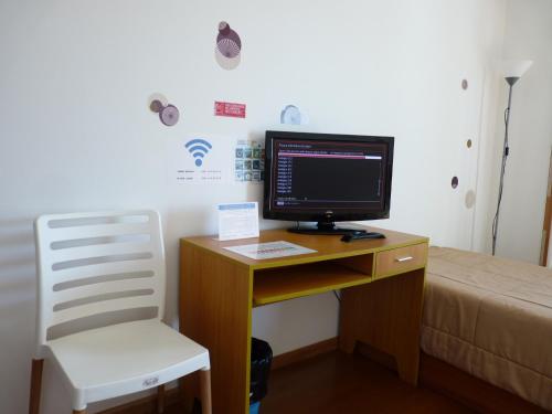 a desk with a computer monitor and a chair in a room at AZORES HOLIDAYS HOUSE -B&B - Suites - Self Check-in KEYBOARD in Ponta Delgada