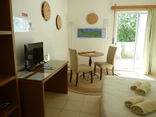 a bedroom with a bed and a desk with a television at AZORES GARDEN HOUSE - Suites B&B and Private Apartments - Self Access KEYBOARD in Ponta Delgada