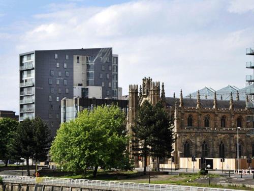 an old church and a tall building in a city at Glasgow City Centre Waterfront Apartment in Glasgow