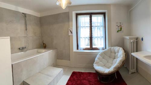 a white bathroom with a tub and a chair in it at l'Attique du Château in Cormondreche