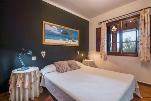 a bedroom with a bed and a table and a window at Sa Vinyeta in Artá