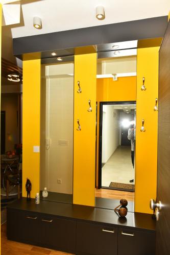 a dressing room with yellow walls and a mirror at Grand Lux apartman in Čačak