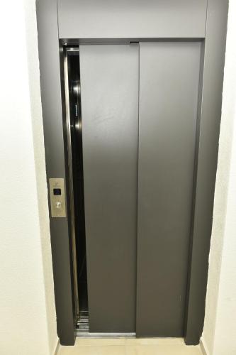 a glass elevator door with a mirror in a bathroom at Grand Lux apartman in Čačak