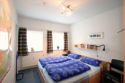 1 dormitorio con cama con sábanas azules y ventana en Gaestehaeuser-Heidehof-Wohnung-1 en Süderhöft