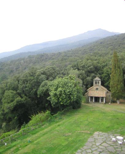 a building in the middle of a field with a mountain at Hotel Sant Bernat in Montseny