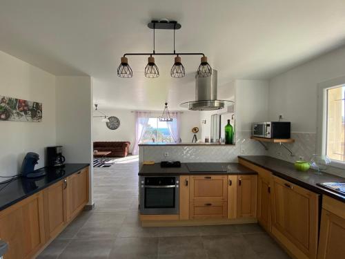 une cuisine avec des placards en bois et des comptoirs noirs dans l'établissement Villa Flora, à La Gaude