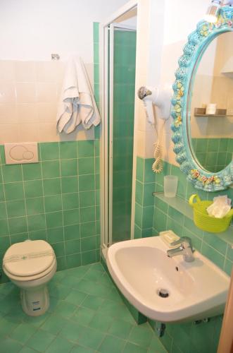 a green tiled bathroom with a toilet and a sink at Roma Gianicolense in Rome