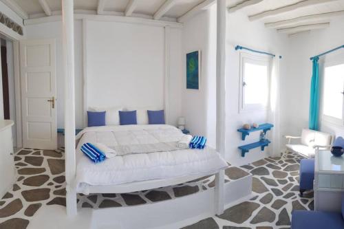a white bedroom with a bed with blue pillows at 4BD Blue Dream Mykonos in Mikonos