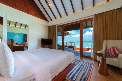 a bedroom with a bed and a view of the ocean at VARU by Atmosphere - Premium All Inclusive with Free Transfers in North Male Atoll