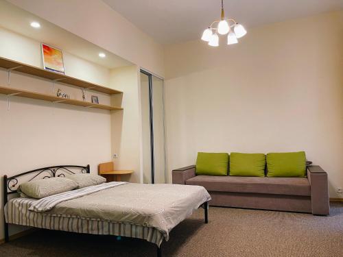 - une chambre avec un lit et un canapé avec des oreillers verts dans l'établissement Odnokomnatnaya studiya, à Kiev