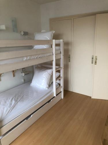 een slaapkamer met 2 stapelbedden met witte kussens bij Appartement lumineux, avec balcon, à 200m de la plage in Hendaye