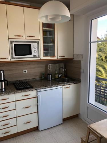 La cuisine est équipée d'un réfrigérateur blanc et d'un four micro-ondes. dans l'établissement Appartement lumineux, avec balcon, à 200m de la plage, à Hendaye