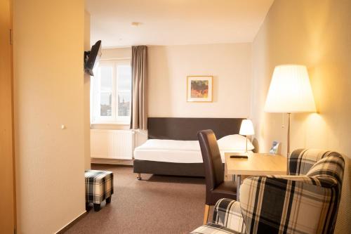 a hotel room with a bed and a table and chairs at Hotel am Schlosspark in Güstrow