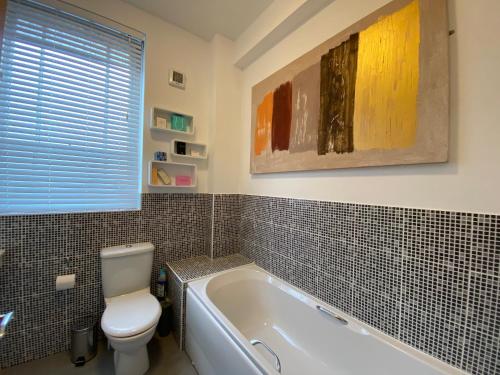 a bathroom with a toilet and a bath tub at Fabulous 2 bed Historic Ground floor apartment Belper with free car parking next to property in Belper