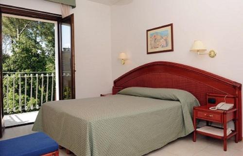 Schlafzimmer mit einem Bett und einem Telefon auf einem Tisch in der Unterkunft Hotel Villa Rosa in Martina Franca