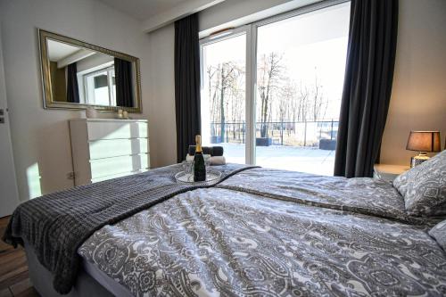 una camera da letto con un letto e una bottiglia di vino sopra di Apartament VILLA PARK przy plaży z widokiem na jezioro, taras 50 m2 a Ostróda