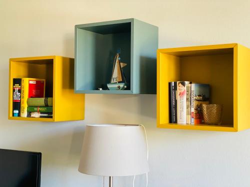 two shelves on a wall with books and a lamp at Kuddels Fischerhus 2 in Börgerende-Rethwisch