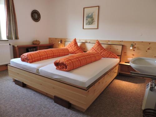 a bed with orange pillows and a sink in a room at Pension Wallnöfer in Mieming