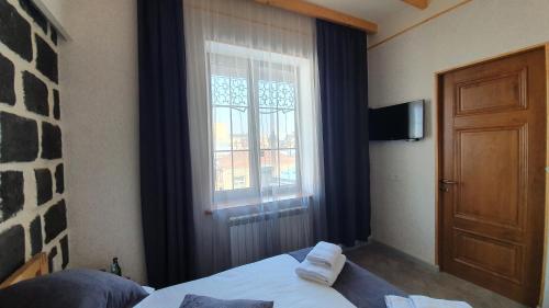 a bedroom with a bed and a window and a door at JINJOTEL Gyumri in Gyumri