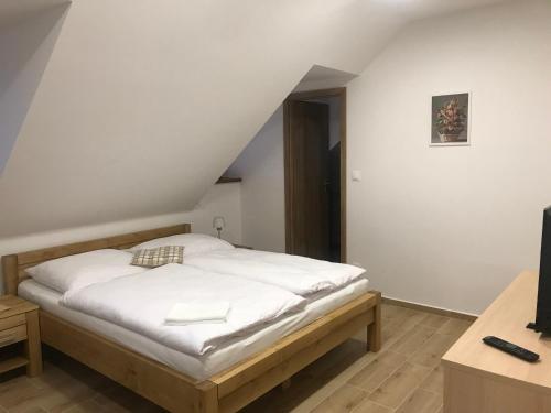 a bedroom with a bed with white sheets and a television at Penzion U Kostela in Kuželov
