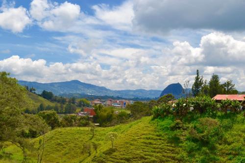 a green hillside with a village and mountains in the background at Roble Colonial - Apartamentos Deluxe en Guatapé in Guatapé