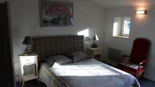 um quarto com uma cama e uma cadeira vermelha em Gîte Les Tilleuls em Beurlay