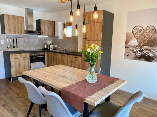 una cocina con una mesa de madera con sillas y un jarrón de flores en Appartement Haus Seerose en Reith im Alpbachtal