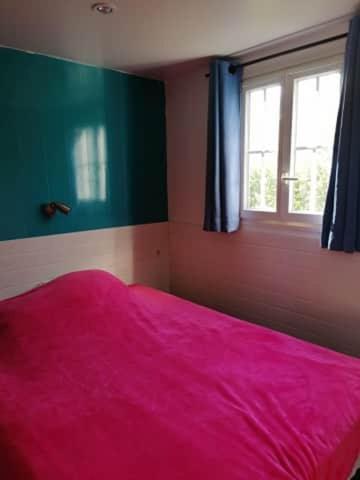 a bedroom with a pink bed and a window at vacances familiales dans camping avec piscine in Fréjus