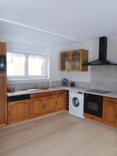a kitchen with wooden cabinets and a washing machine at Logement douillet neuf L'INDIAN in Dossenheim-sur-Zinsel