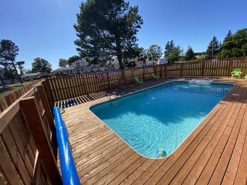 a swimming pool on a deck with a wooden fence at The Pines Motel and Cottages in Rustico