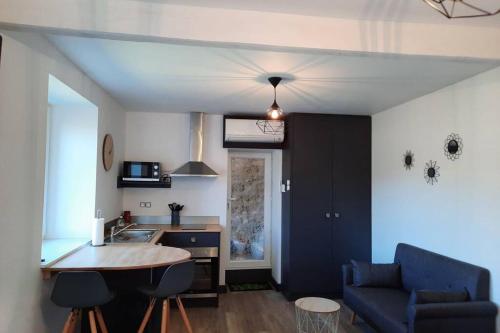 eine Küche und ein Wohnzimmer mit einem Sofa und einem Tisch in der Unterkunft Studio avec vue sur la vezere in Uzerche