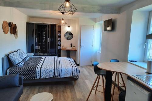 ein Schlafzimmer mit einem Bett und einem Tisch in einem Zimmer in der Unterkunft Studio avec vue sur la vezere in Uzerche