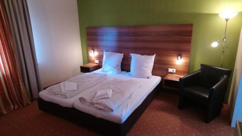 um quarto de hotel com uma cama e uma cadeira em ParkHotel Nieheim em Nieheim