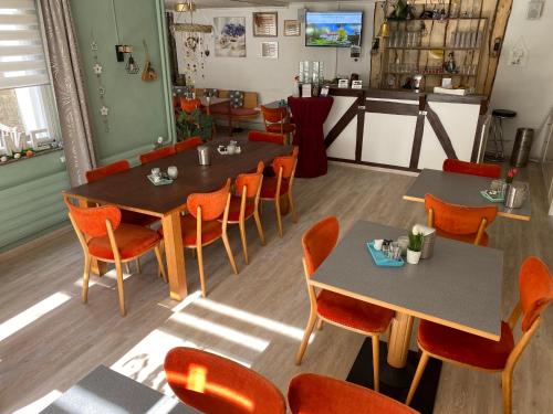 a restaurant with two tables and orange chairs at Hotel Pension Gelpkes Mühle in Bad Sachsa