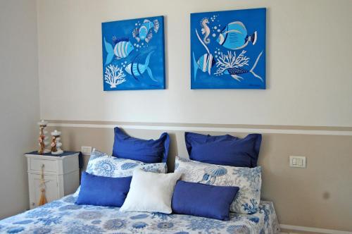 a bed with blue pillows and three pictures on the wall at SeaBaudia 2 SENZA TERRAZZA in Sabaudia