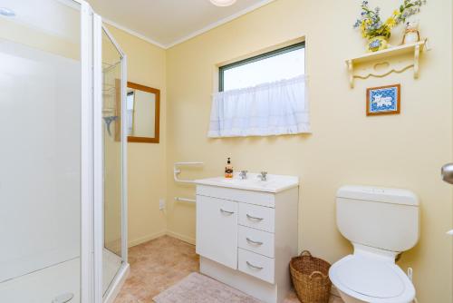 a bathroom with a toilet and a shower at Hibiscus House - Mangawhai Heads Holiday Home in Mangawhai