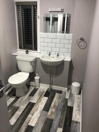 a bathroom with a toilet and a sink at Sinclair Bay Apartments in Keiss