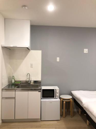 una cocina con fregadero y una cama en una habitación en Oku Apartment en Tokio