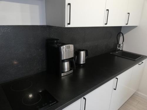 a kitchen with a black counter top with a coffee maker at AL Mare Apartament in Gdańsk