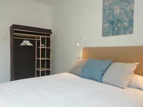 Bett mit weißer Bettwäsche und blauen Kissen in einem Zimmer in der Unterkunft Estudio Porto in San José