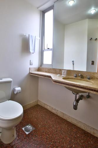 a bathroom with a toilet and a sink and a mirror at Transamerica Belo Horizonte Lourdes in Belo Horizonte