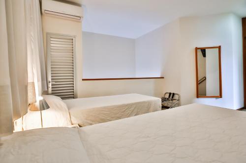 two white beds in a room with a mirror at Transamerica Belo Horizonte Lourdes in Belo Horizonte