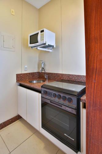 a kitchen with a stove and a microwave at Transamerica Belo Horizonte Lourdes in Belo Horizonte