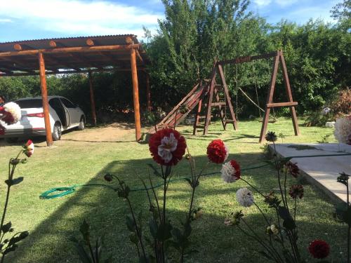a swing set in a yard with flowers at Posada La Sofia in Tafí del Valle