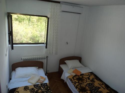two beds in a small room with a window at Pansion Modana Medjugorje in Međugorje