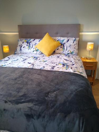 a bedroom with a large bed with a yellow pillow at lovely 1 bedroom borders cottage in Town Yetholm