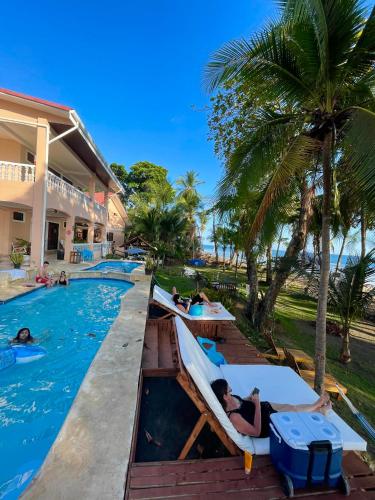 a pool at a resort with people laying on beds at Hotel Beachfront Vista Hermosa in Jacó