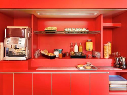 a kitchen with red walls and a counter with food at hotelF1 Le Mans Nord in Saint-Saturnin