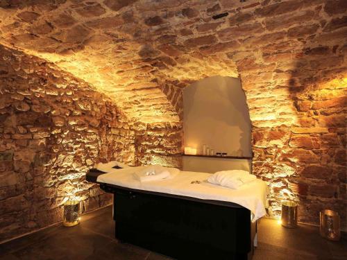 a spa room with a bed in a stone wall at 5 Terres Hôtel & Spa Barr - MGallery Hotel Collection in Barr